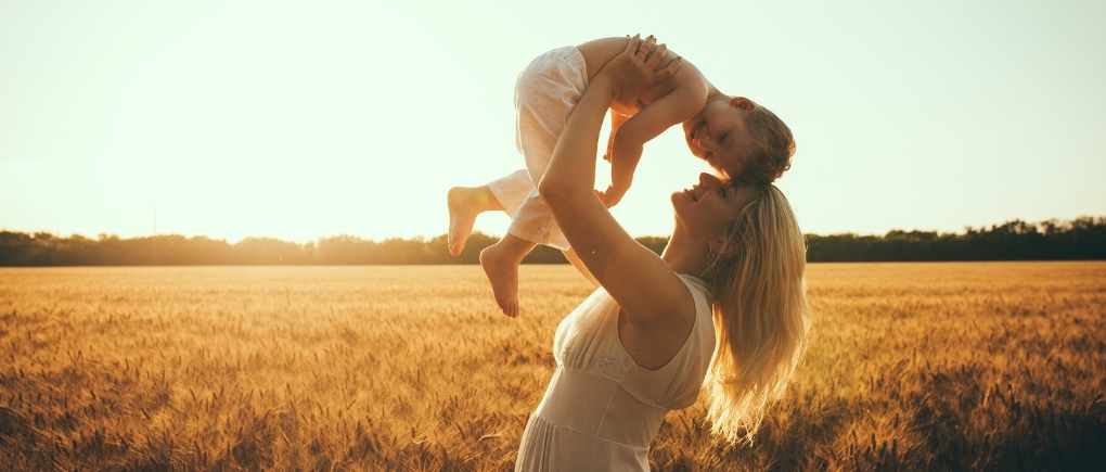 woman holding her preschool son in a field