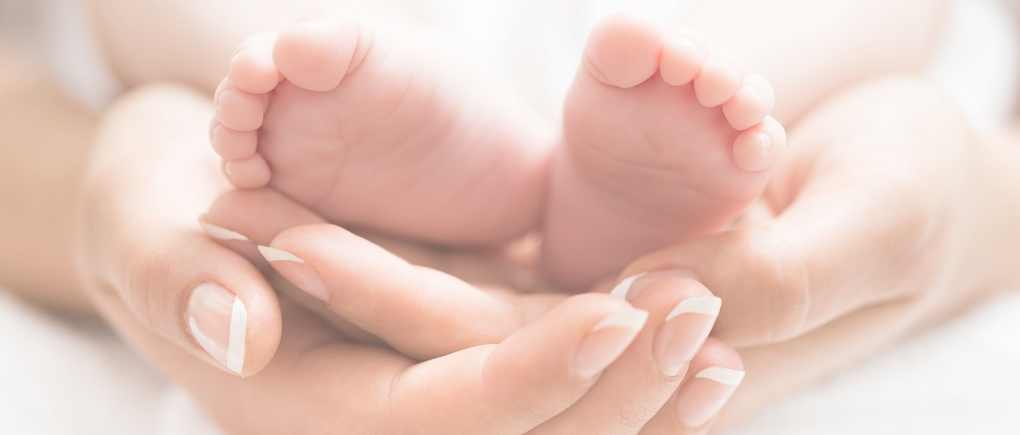 mother's hands gently cradling baby feet