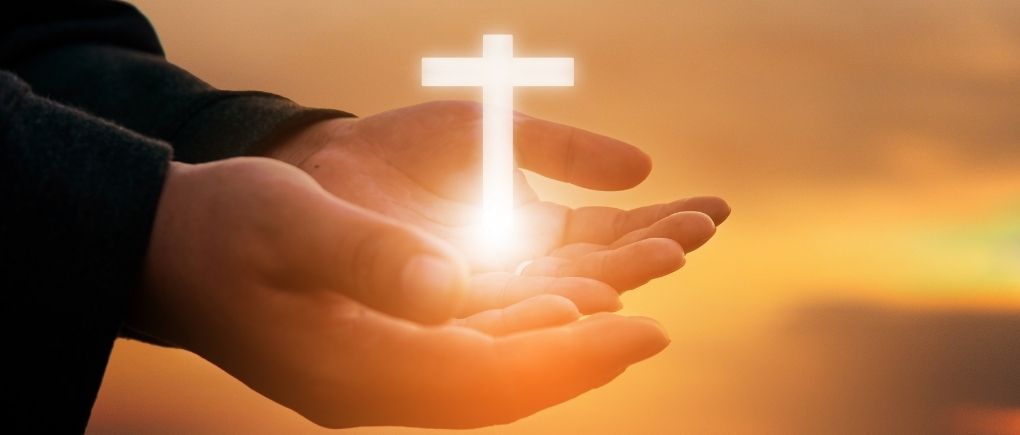 hands holding a glowing cross